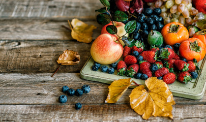 Fresh fruits. Assorted fruits colorful background. Organic food. Fresh raw fruits, berries and fall leaves. Autnum harvest. Flat lay. Copy space.