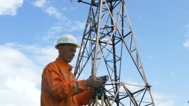 professional surveyor in white helmet adjusts dumpy level