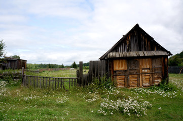 old wooden house with a grazing horse in the yard