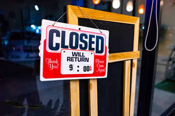 closed sign of the shop hanging on the glass door