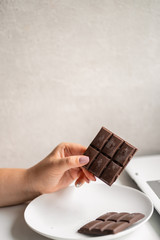 Sugar addiction, stressful lifestyle, dietary and medical concept. Young woman breaking chocolate bar. Mindless snacking, daily routine and unhealthy eating