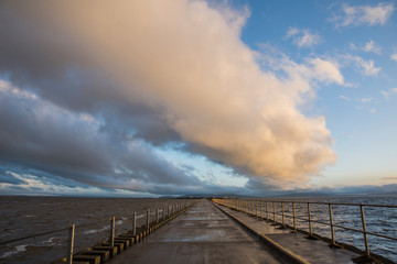 Giant yellow and blue clouds over the long pier in Galway bay, Ireland