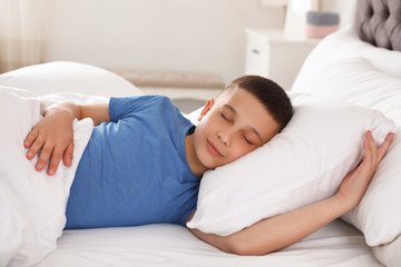 Portrait of cute boy sleeping in large bed © New Africa