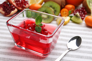 Glass bowl of tasty jelly and spoon on table