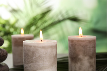 Obraz na płótnie Canvas Burning aromatic candles on blurred green background