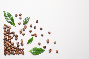 Fresh green coffee leaves and beans on light background, flat lay. Space for text