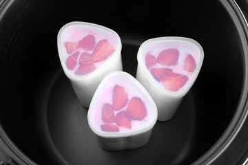 Obraz na płótnie Canvas Cups of homemade strawberry yogurt in modern multi cooker, closeup view