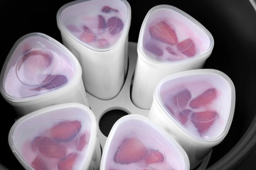 Cups of homemade strawberry yogurt in modern multi cooker, closeup view