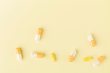 A few white-yellow drug capsules on the yellow background