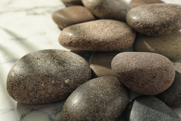 Fototapeta na wymiar Pile of spa stones on marble table, closeup