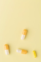 A few white-yellow drug capsules on the yellow background