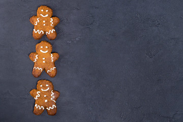 Frame from Christmas cookies - gingerbread man, white glaze on gray concrete background. Recipe, invitation concept. Top view, flat lay, close-up, copy space, layout design