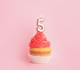 Birthday cupcake with number five candle on pink background