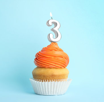 Birthday cupcake with number three candle on blue background