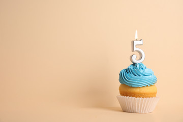 Birthday cupcake with number five candle on beige background, space for text