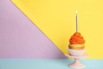 Birthday cupcake with candle on stand against color background, space for text