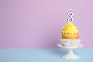 Birthday cupcake with number three candle on stand against color background, space for text