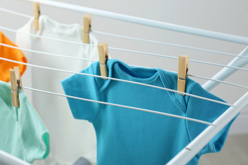Different cute baby onesies hanging on clothes line. Laundry day