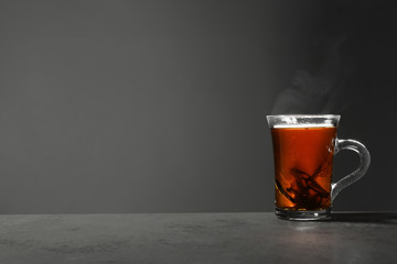 Glass cup of hot leaf tea on stone table against grey background, space for text