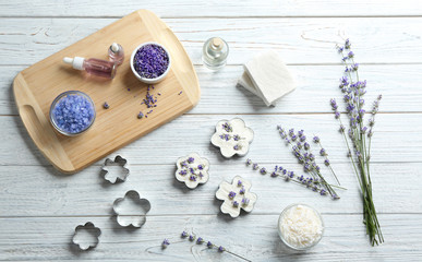 Flat lay composition of handmade soap bars with lavender flowers and ingredients on white wooden background