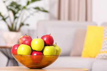 Bowl with different sweet apples on table in living room, space for text