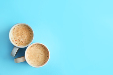 Cups of coffee on blue background, top view. Space for text