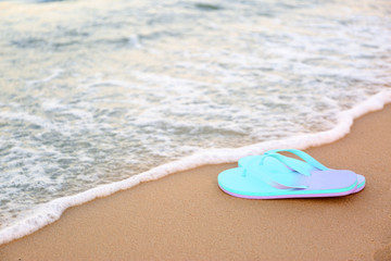 Fototapeta na wymiar Stylish flip flops on sand near sea, space for text. Beach accessories