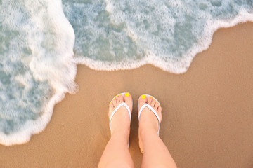 Top view of woman with white flip flops on sand near sea, space for text. Beach accessories