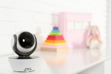Baby camera on table near white brick wall, space for text. Video nanny
