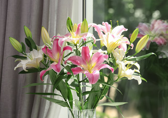 Vase with bouquet of beautiful lilies near window, closeup