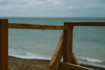 Abstract nature photography. Sandy beach and stairs with wooden railings. View of the sea through old wooden handrails with the sea in the background.