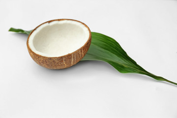 Half of fresh coconut and palm leaf on white background
