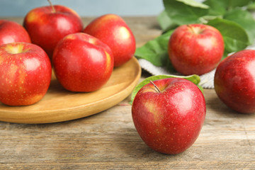 Ripe juicy red apples on wooden table against blue background