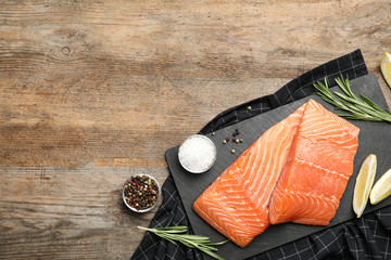 Flat lay composition with tasty salmon fillet on wooden table. Space for text