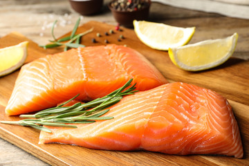 Wooden board with salmon fillet on table, closeup