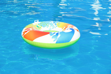 Colorful inflatable ring floating in swimming pool on sunny day