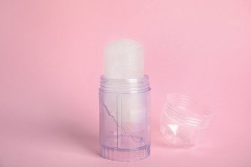 Fototapeta na wymiar Natural crystal alum stick deodorant and cap on pink background