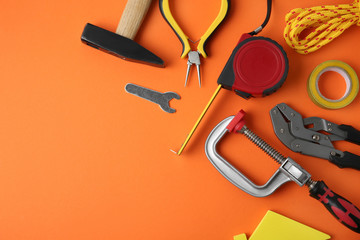 Set of repair tools on orange background, flat lay. Space for text