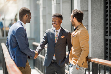 three handsome adult men in suits communicate