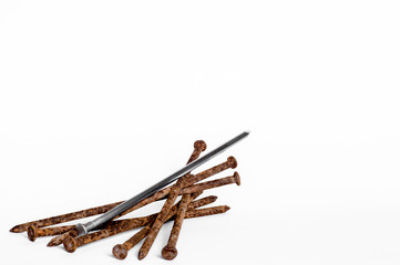 Metal shiny sharp nail in the center of a pile of old rusty nails on a white background.