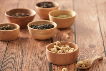 assortment of dry tea in white bowls on wooden surface