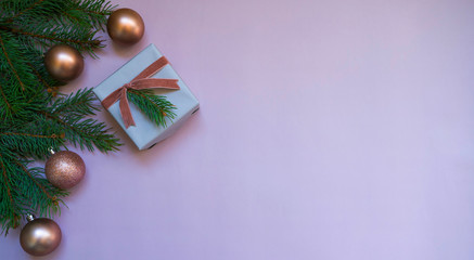 Christmas card concept with fir tree branches, gift and pink shiny balls on light background - text space. Merry Christmas and Happy Holidays greeting card. Flat lay, top view. Copy space for text.