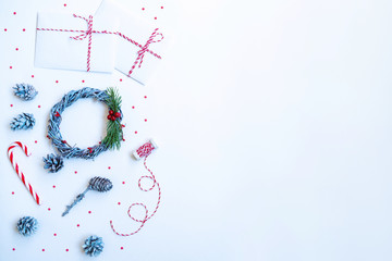Christmas composition. Gifts, fir tree branches with cones, red decorations on light background. Christmas, winter, new year concept. Flat lay, top view, copy space.