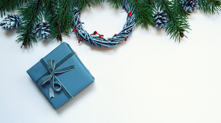 Christmas composition. Wreaths, red berries, fir branches, blue gift box and pine cones on pastel gray background. Christmas, winter, new year concept. Flat lay, top view, copy space.