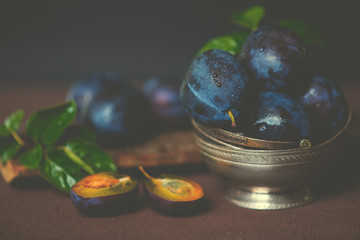 Bowl with ripe juicy plums on table. Fresh organic plums. Summer harvest. Autumn harvest. Beautiful still life. Toned image. Selective focus.