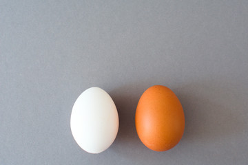 Two eggs, white and brown on the  gray background