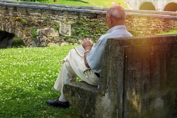 senior man sitting on park bench reading