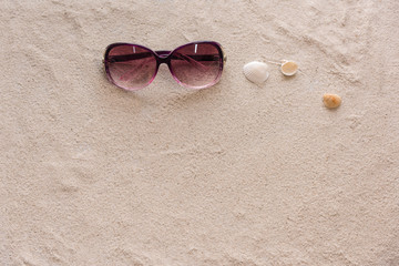 Fototapeta na wymiar Creative travel background with a pink lady sunglasses and shells on the beach