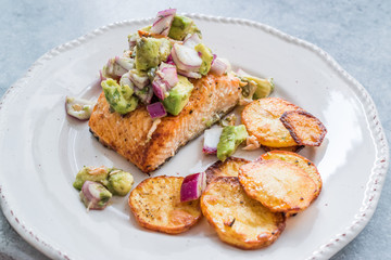 Salmon Fish Fillet with Avocado, Red Onions and Baked Round Potato Slices in Seafood Plate.