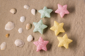 Fototapeta na wymiar Dream of a combination of white seashells and decorative colored stars on a sandy beach background